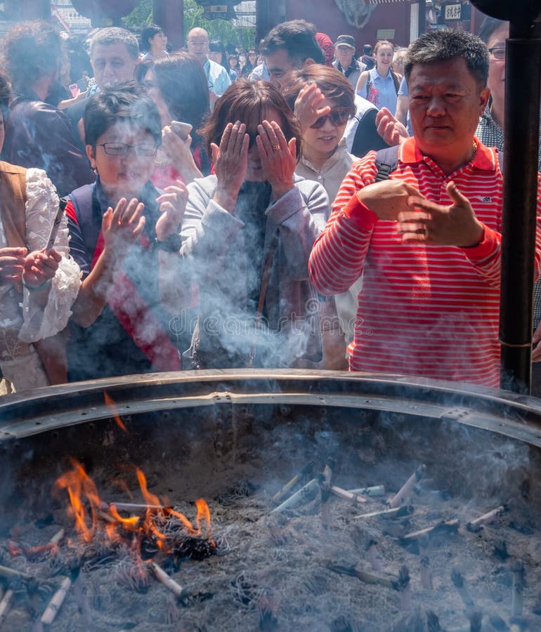 Tourists At Sensoji Temple Incense Burner, Tokyo, Japan. Tokyo, Japan - April 28th, 2017. Tourist drawing smoke believe to have healing properties from Jokoro or royalty free stock photos