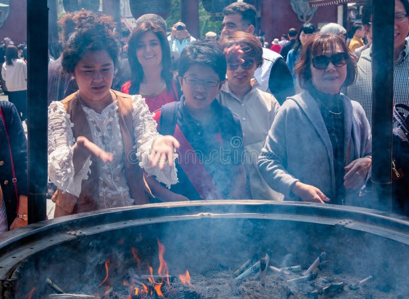 Tourists At Sensoji Temple Incense Burner, Tokyo, Japan. Tokyo, Japan - April 28th, 2017. Tourist drawing smoke believe to have healing properties from Jokoro or stock image